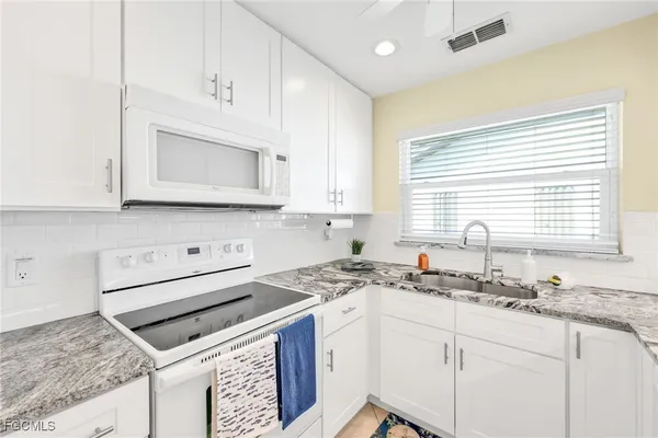 a kitchen with stainless steel appliances granite countertop a stove a sink and a microwave