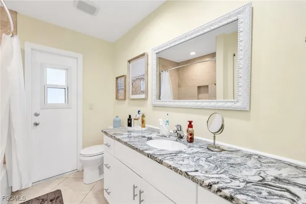 a bathroom with a granite countertop sink a toilet and a mirror