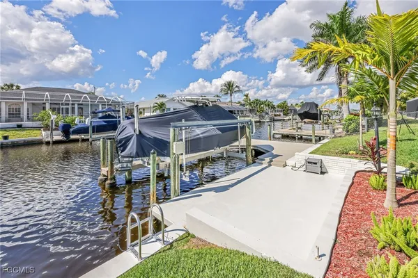 a backyard of a house with table and chairs plants and large tree