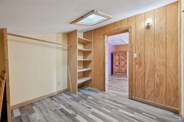 a view of a hallway with wooden floor and a bathroom