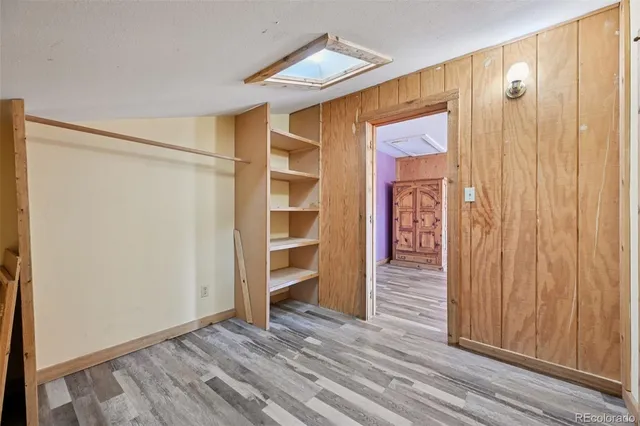 a view of a hallway with wooden floor and a bathroom