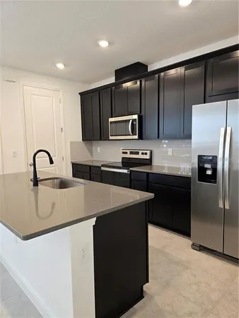 a kitchen with stainless steel appliances kitchen island a sink stove and refrigerator
