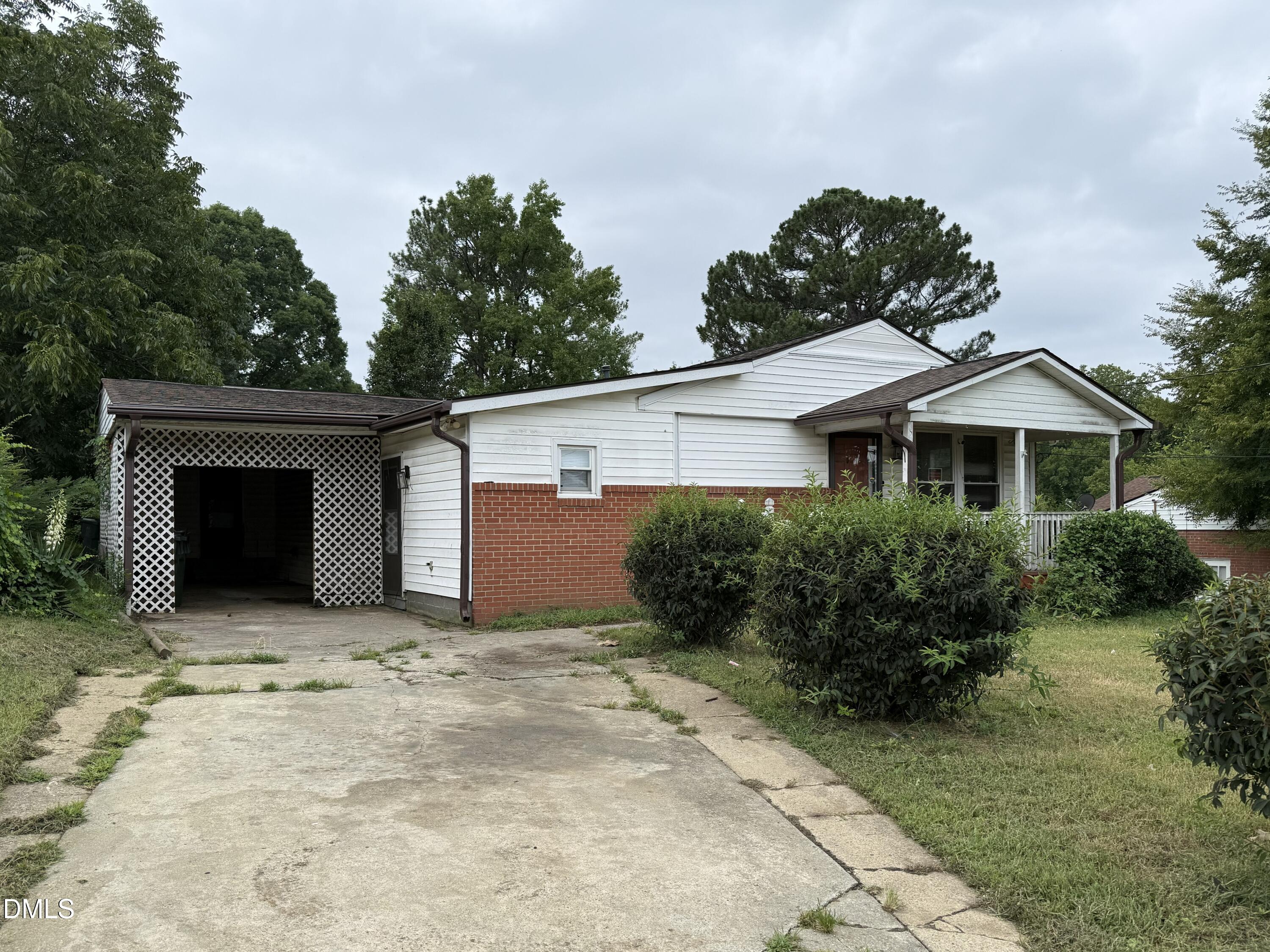 Exterior featuring white siding, a brick foundation, a covered carport, and a covered porch