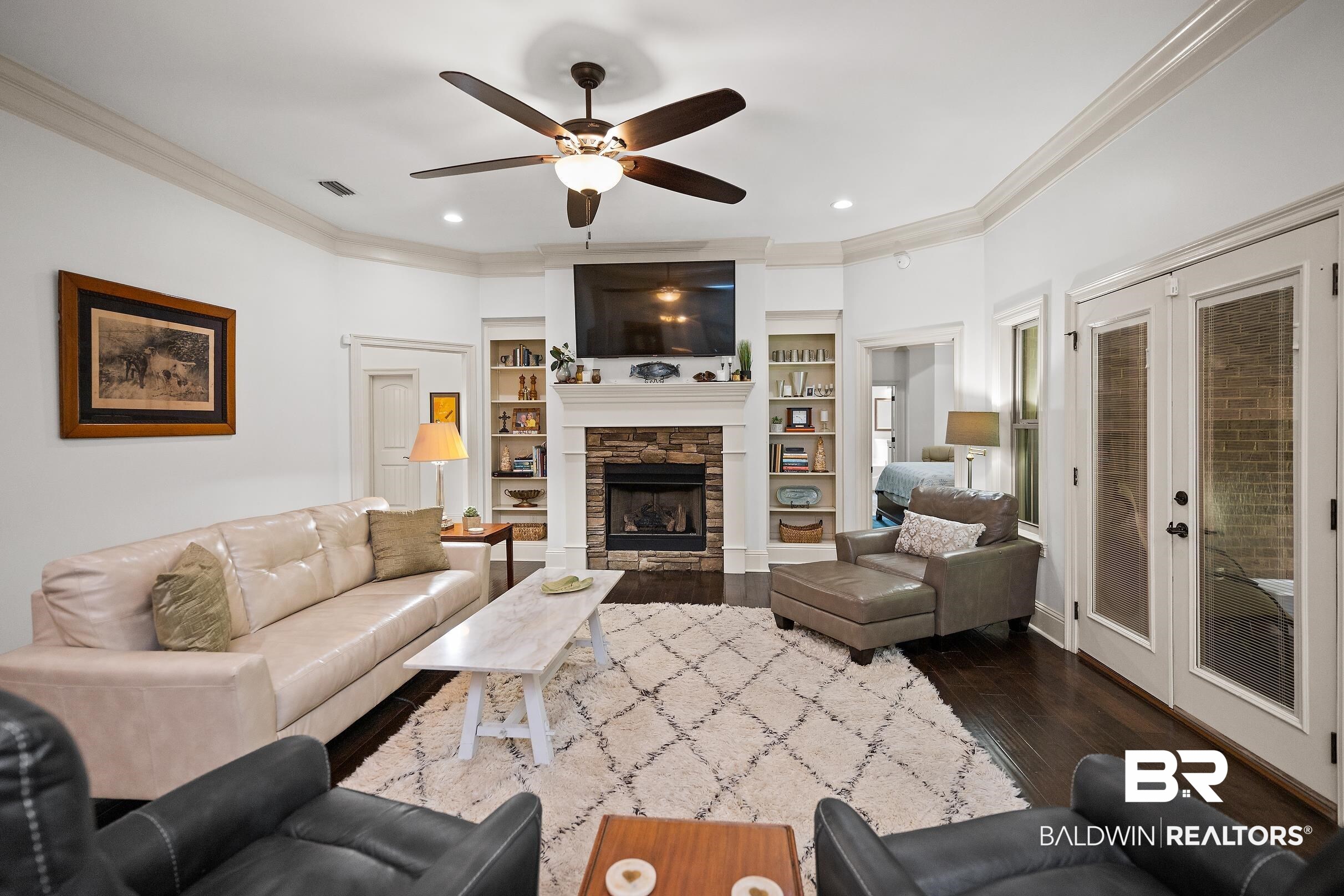 313 Pecan Ridge Boulevard Fairhope, AL 36532 - Photo 4 of 51 Bright living area featuring dark wood-finish flooring, a stone-faced fireplace with a white mantel, and built-in shelving