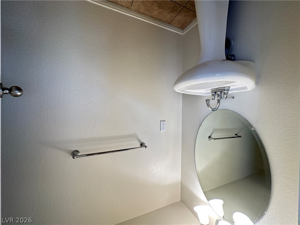 7305 Prussian Green Street Las Vegas, NV 89139 - Photo 16 of 23 A corner pedestal sink with a mirror and wall-mounted towel bars create a functional bathroom.