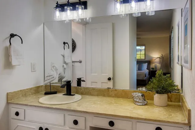 a bathroom with a granite countertop sink a mirror and shower
