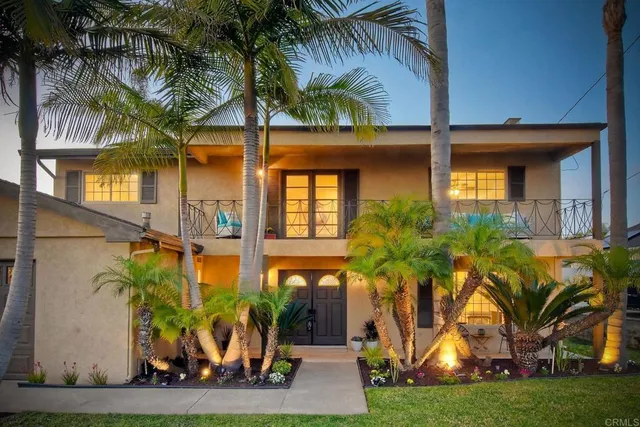 front view of house with a yard and palm trees