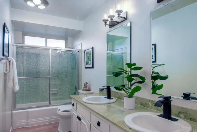 a bathroom with a granite countertop sink a toilet and shower