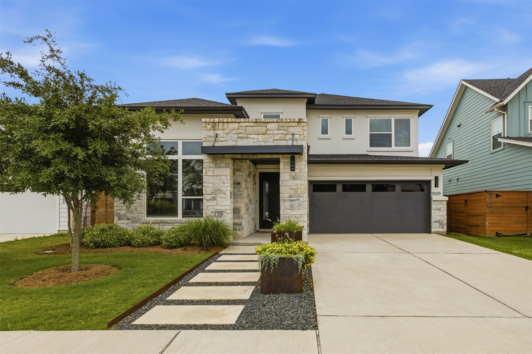 Contemporary two-story residence featuring a stone and stucco facade, and a two-car garage