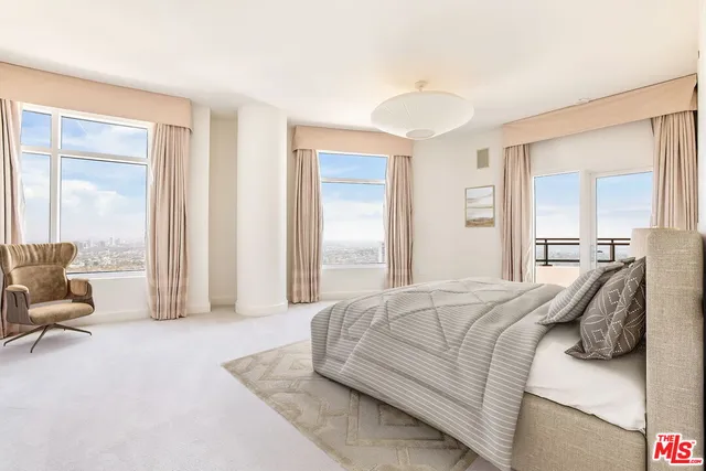 a bedroom with a bed and large windows