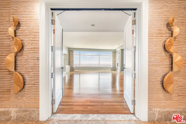 a view of a hallway with wooden floor and a bathroom