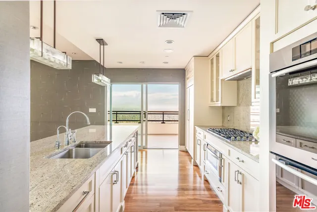 a kitchen with granite countertop a stove a sink and a refrigerator