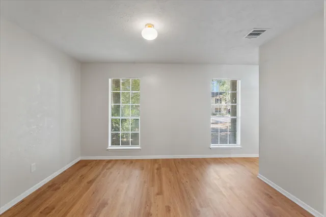 an empty room with wooden floor and windows