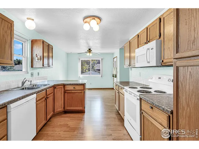 a kitchen with stainless steel appliances granite countertop a stove top oven a sink dishwasher and white cabinets with wooden floor