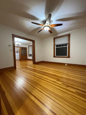 a view of an empty room with wooden floor and a window