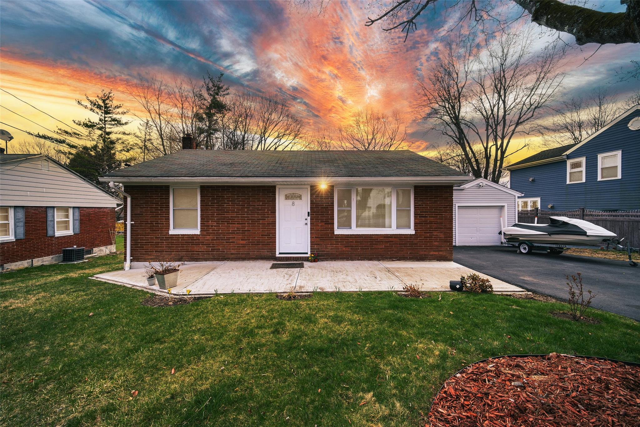 a front view of a house with a garden and trees