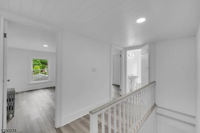 a view of hallway with window and wooden floor