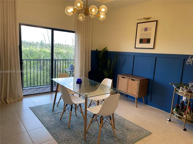 a view of a dining room with furniture a chandelier and a window
