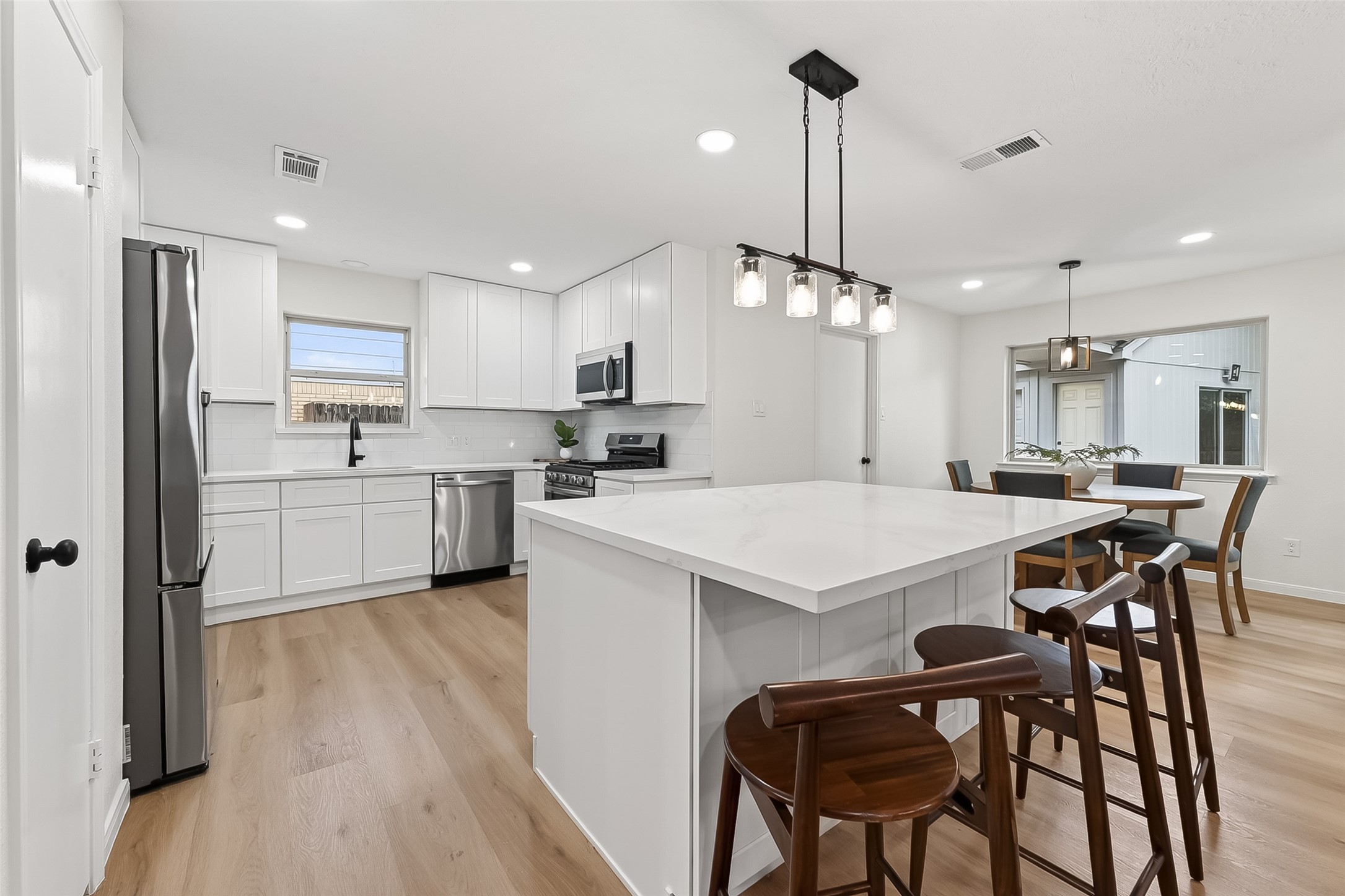 2914 Riata Lane Houston, TX 77043 - Photo 15 of 46 a kitchen with stainless steel appliances kitchen island granite countertop a table chairs a sink dishwasher a refrigerator and cabinets with wooden floor