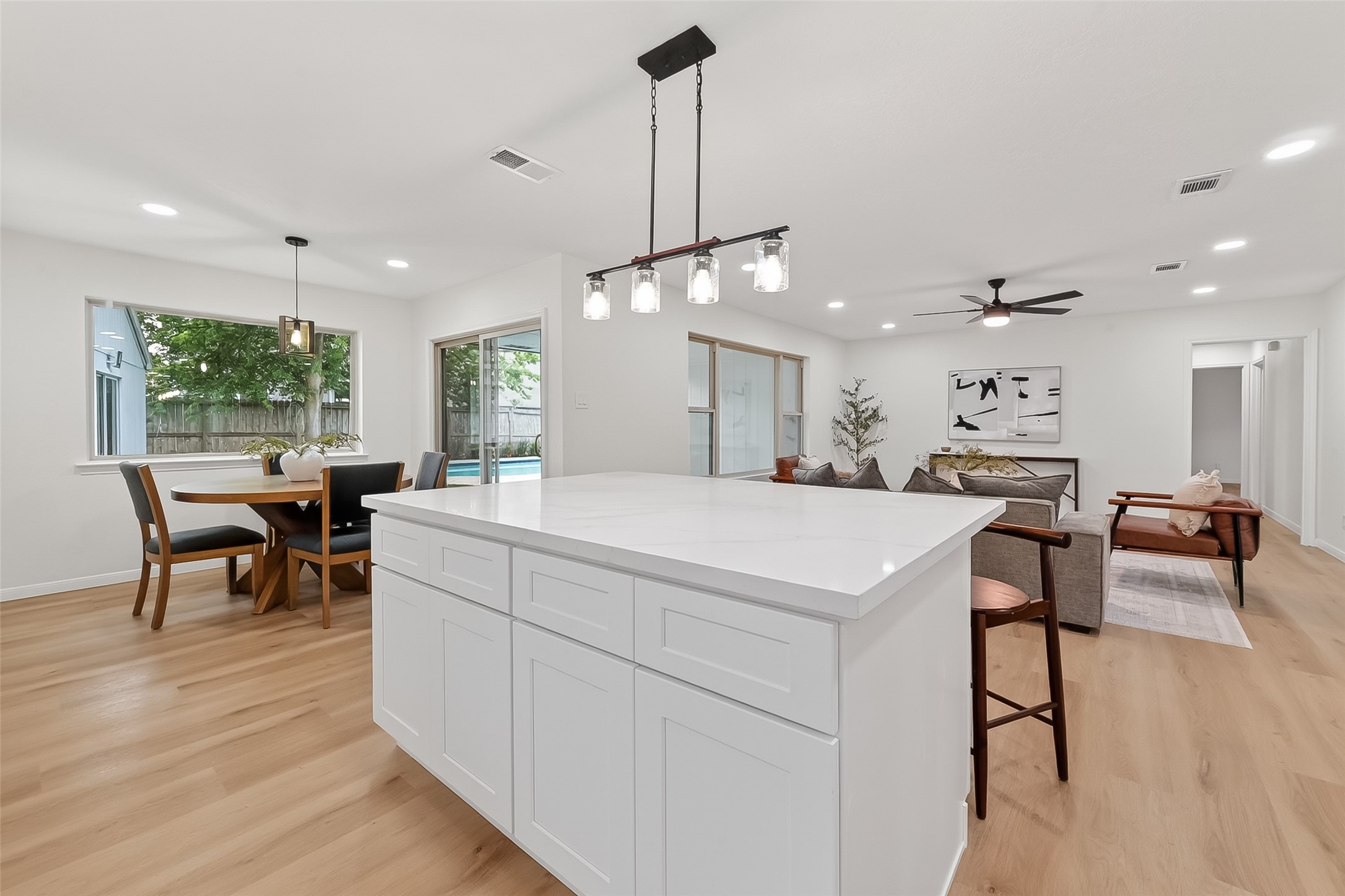 2914 Riata Lane Houston, TX 77043 - Photo 19 of 46 a large white kitchen with living room a stove a dining table and chairs with wooden floor