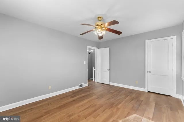 an empty room with wooden floor chandelier fan and closet area