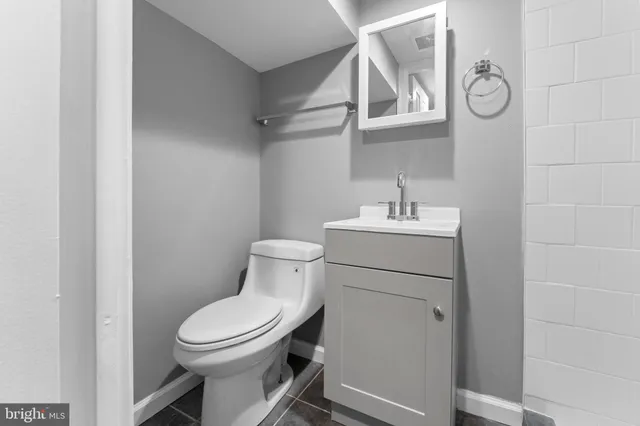 a bathroom with a toilet sink vanity and mirror