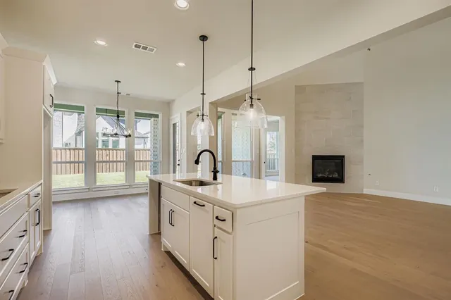 a kitchen with stainless steel appliances granite countertop a sink a window and a wooden floor