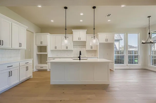 a large white kitchen with wooden floor