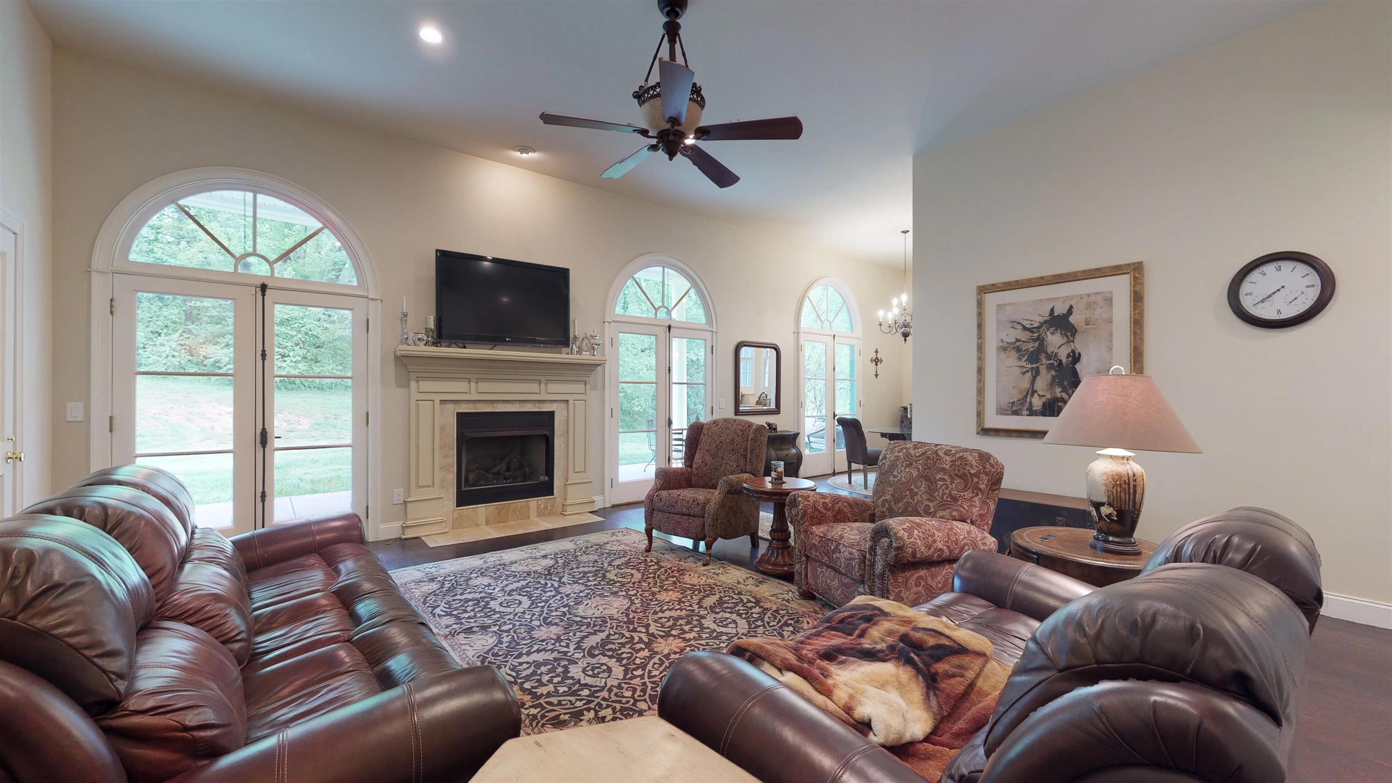 Warm and inviting Great Room with French doors with arched transoms and hardwood floors opens to covered back porch