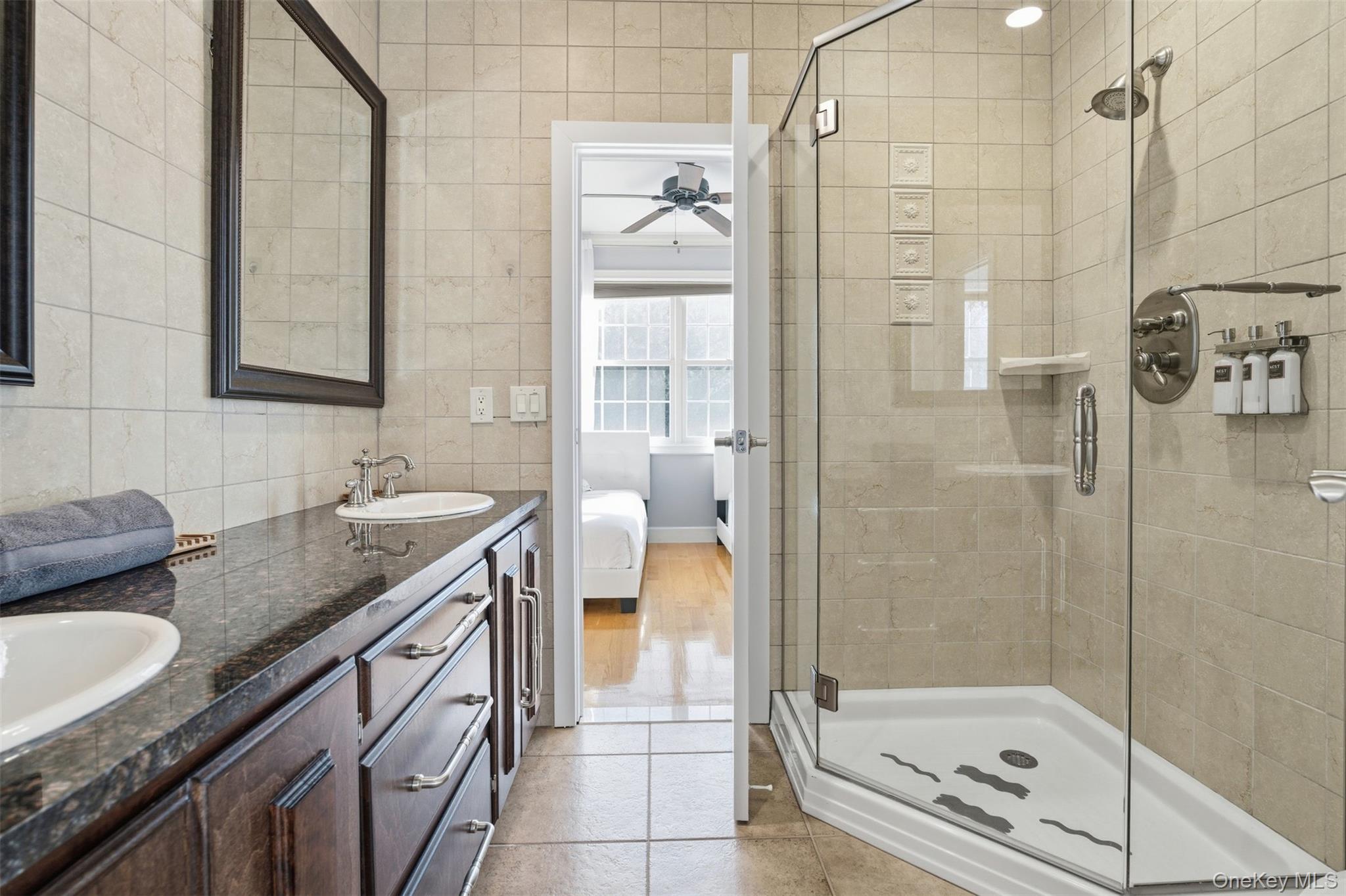 33 A Newtown Road Hampton Bays, NY 11946 - Photo 41 of 50 Bathroom featuring ensuite bath, double vanity, a shower stall, light tile patterned flooring, and a ceiling fan