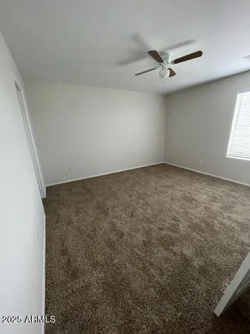 an empty room with a ceiling fan and window