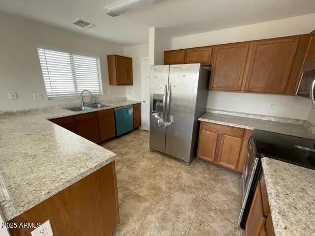 a kitchen with stainless steel appliances granite countertop a refrigerator a stove and a sink
