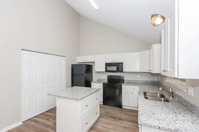 a kitchen with granite countertop a sink a stove top oven and stainless steel appliances