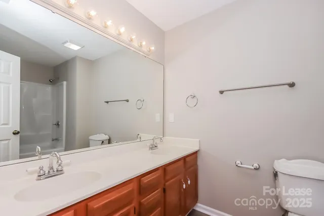 a bathroom with a double vanity sink toilet and a mirror