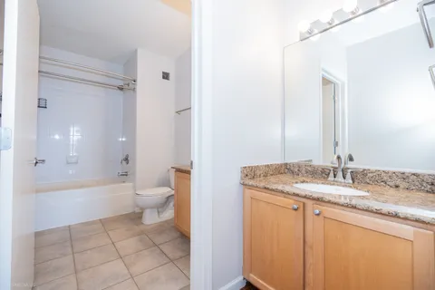 a bathroom with a granite countertop sink a toilet and a large mirror