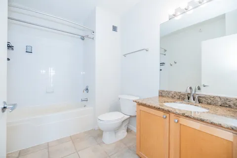 a bathroom with a granite countertop sink a toilet and shower