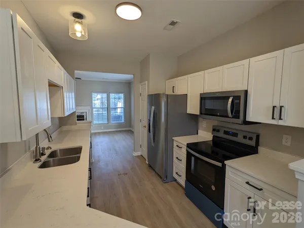a kitchen with stainless steel appliances a refrigerator a stove a sink dishwasher and a microwave oven with wooden floor