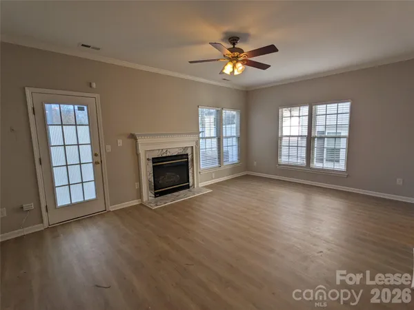 an empty room with wooden floor fireplace and windows