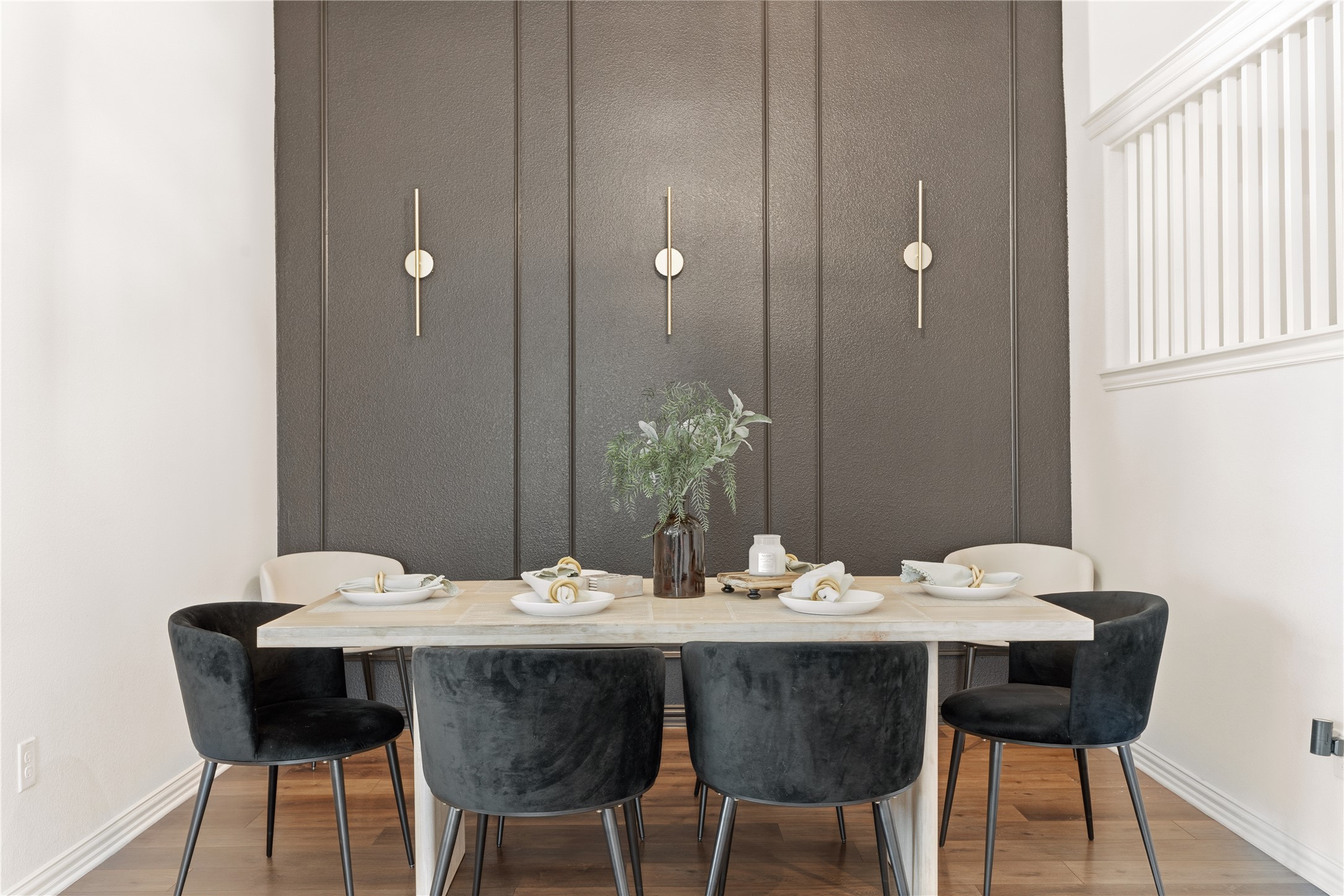 486 Pond View Pass Buda, TX 78610 - Photo 10 of 39 Dining area featuring a dark accent wall with vertical paneling and three wall-mounted sconces