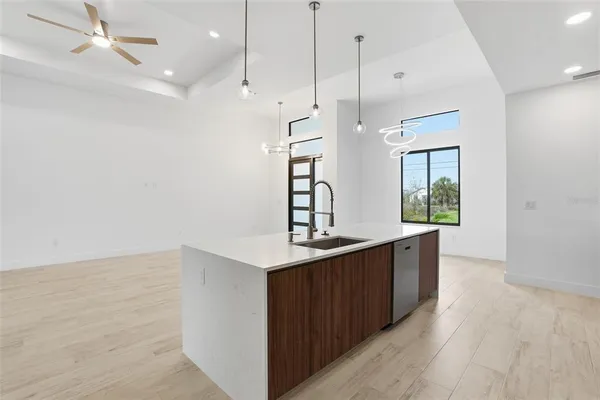 an empty room with wooden floor ceiling fan and windows