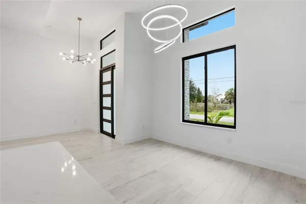 an empty room with chandelier fan and windows