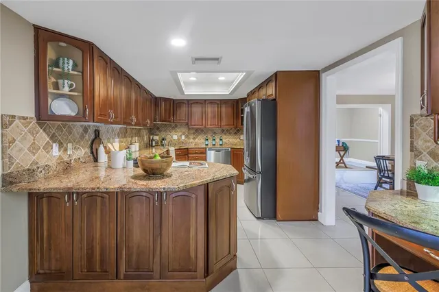 a kitchen with granite countertop a stove a refrigerator and wooden cabinets