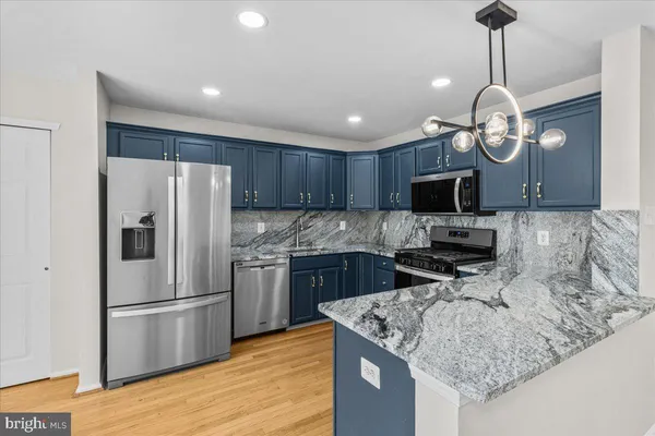 a kitchen with stainless steel appliances granite countertop a refrigerator a oven a sink and a chandelier