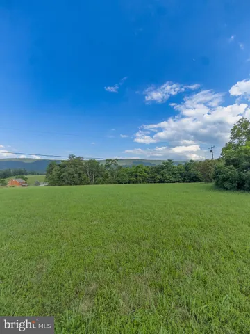 a view of a green field with wooden fence