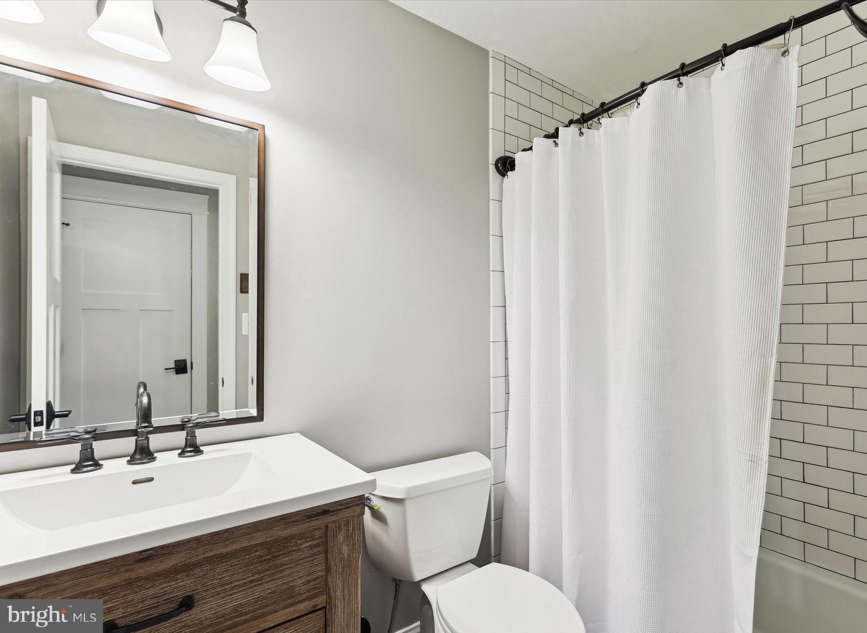 11476 Bronzedale Drive Oakton, VA 22124 - Photo 47 of 82 a bathroom with a sink a toilet a mirror and shower curtain