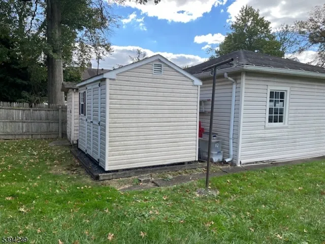 a view of a white house that has a small yard and large trees