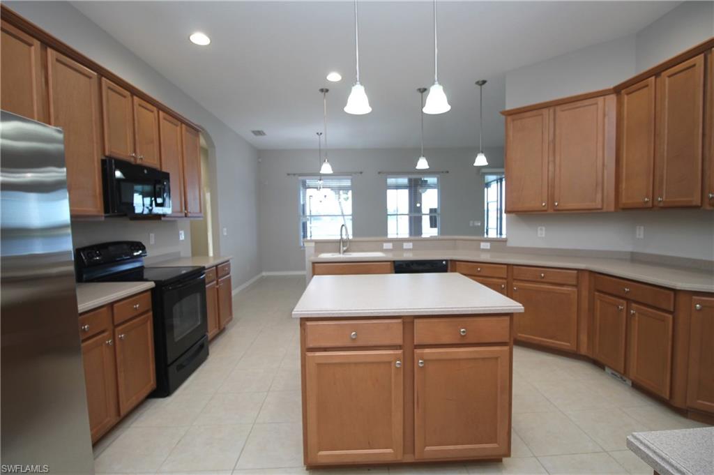 2086 Grove Drive Naples, FL 34120 - Photo 11 of 24 a kitchen with kitchen island granite countertop wooden cabinets and a sink