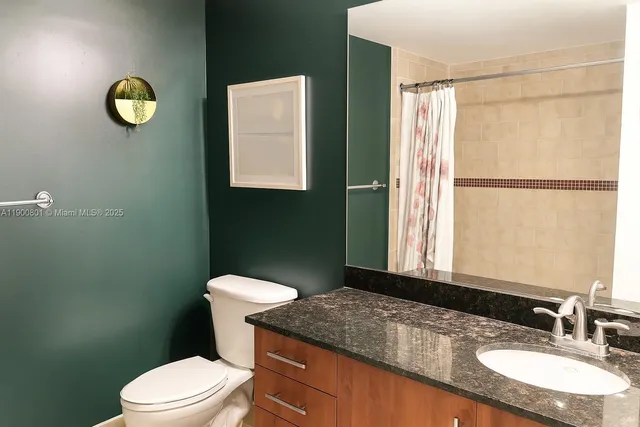 a bathroom with a granite countertop sink toilet and a mirror