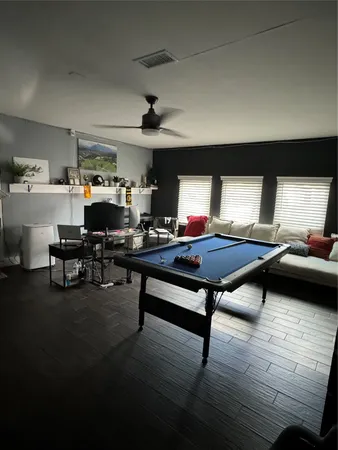 a view of a swimming pool with lawn chairs and large trees