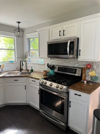 a kitchen with stainless steel appliances a refrigerator sink and white cabinets